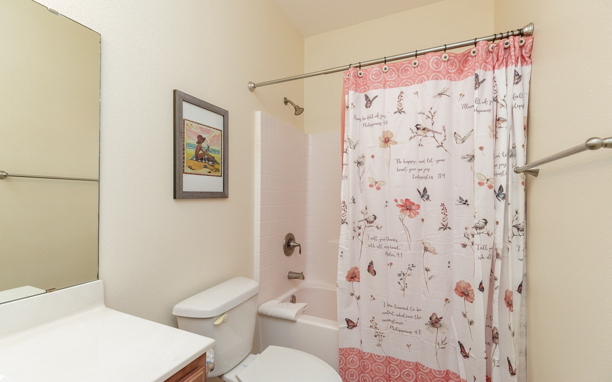 Step into your private bathroom featuring a relaxing tub-shower combo with inspiring floral curtains and thoughtful touches.