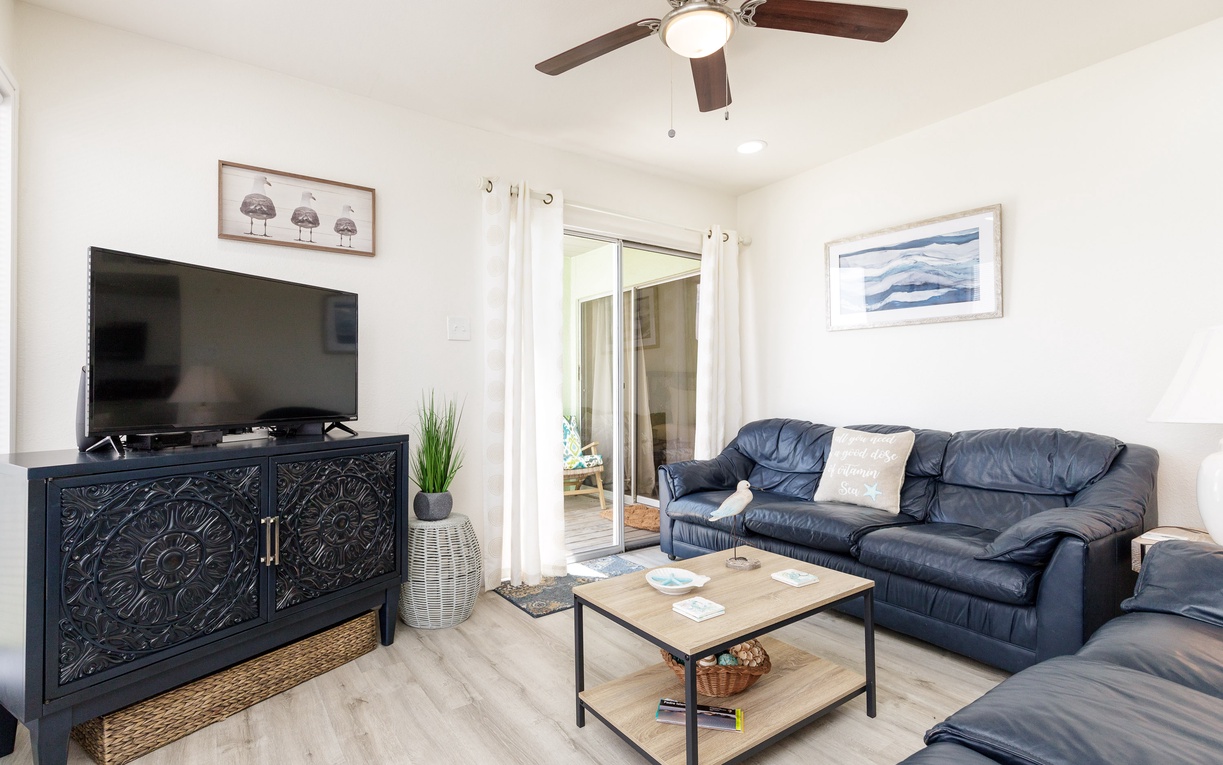 Unwind in your cozy living room with plush leather seating, entertainment center, and peaceful patio access for ultimate relaxation.