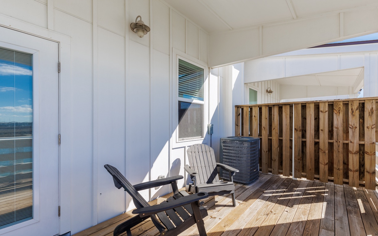 Your private balcony beckons with comfortable seating and warm sunlight streaming across the wooden deck.