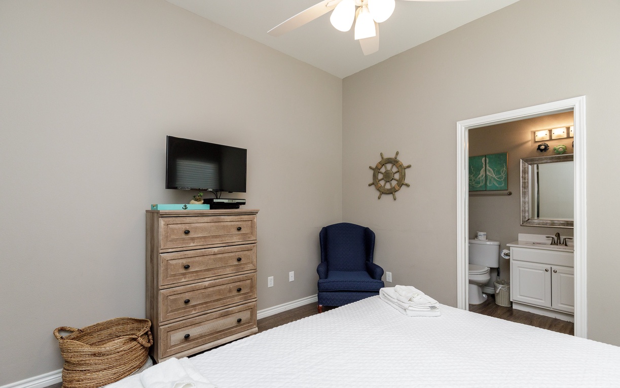 Sink into comfort in your nautical-themed bedroom featuring a cozy armchair, king size bed, and convenient en-suite bathroom access.