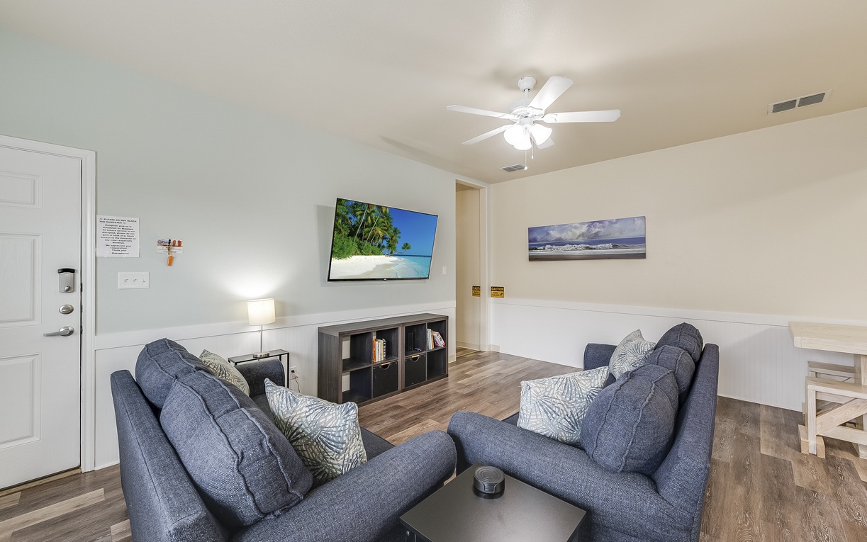Sink into plush blue sofas while tropical artwork transports your mind to paradise in this cozy living space.