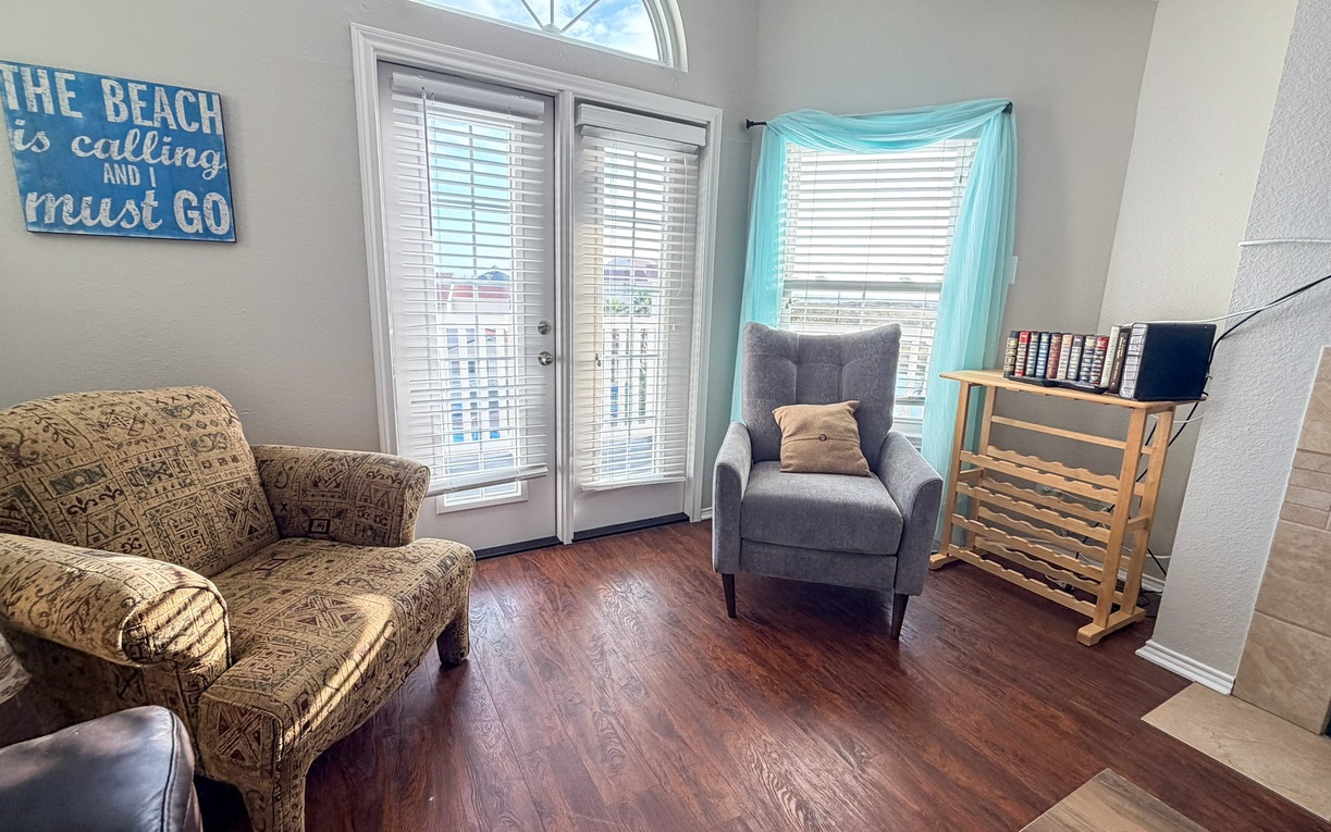 Unwind in your cozy living room with comfortable seating, natural light streaming through French doors, and charming beach decor.