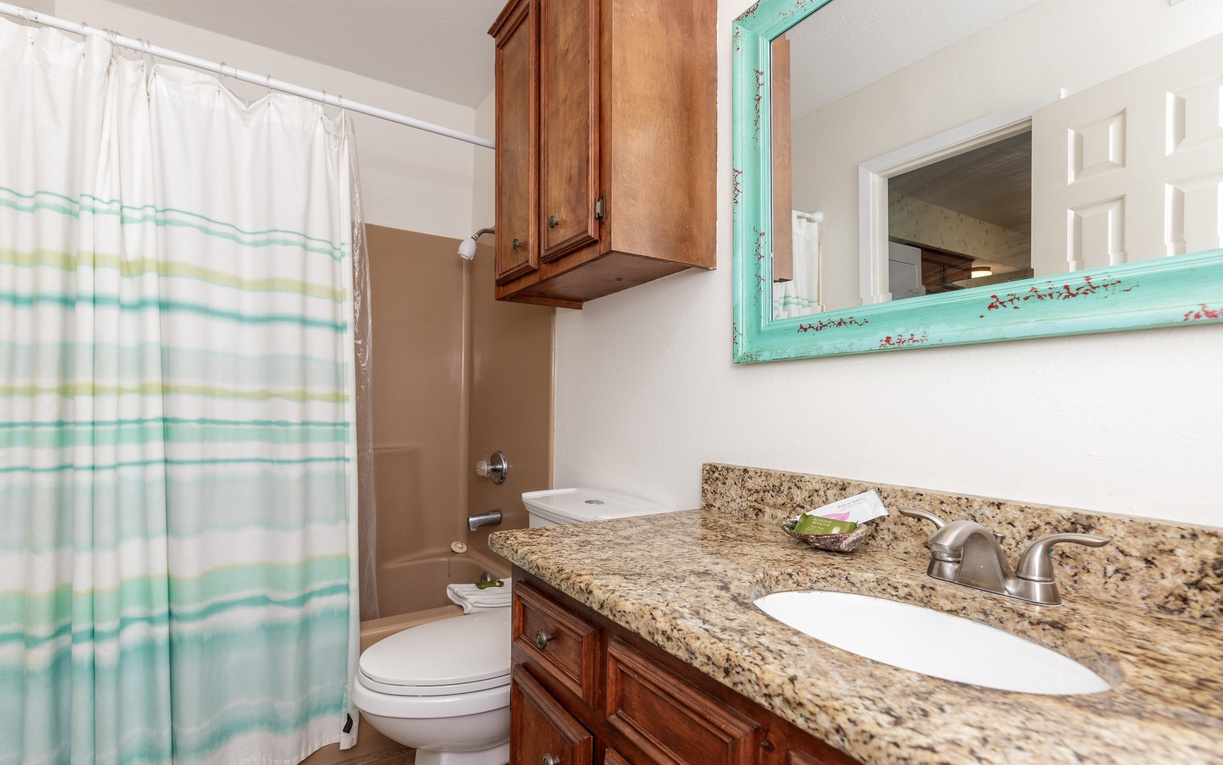 Your private bathroom features granite countertops, warm wood cabinetry, and a refreshing shower-tub combo for your comfort.