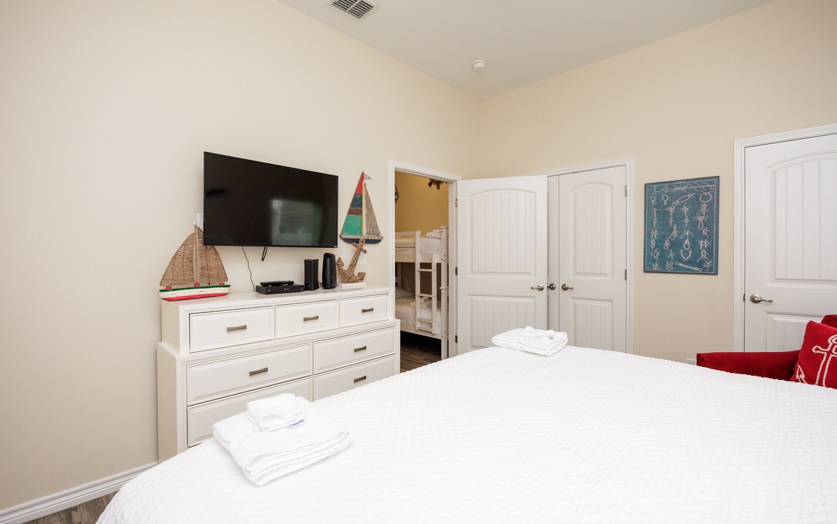 Relax in your cozy bedroom featuring nautical touches, crisp white linens, and a flat-screen TV for unwinding after beach days.