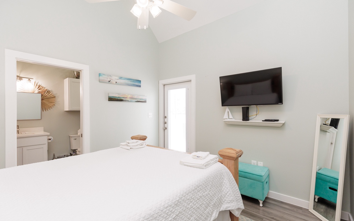Your bright, peaceful bedroom features a comfortable bed, wall-mounted TV, and turquoise storage bench for ultimate relaxation.