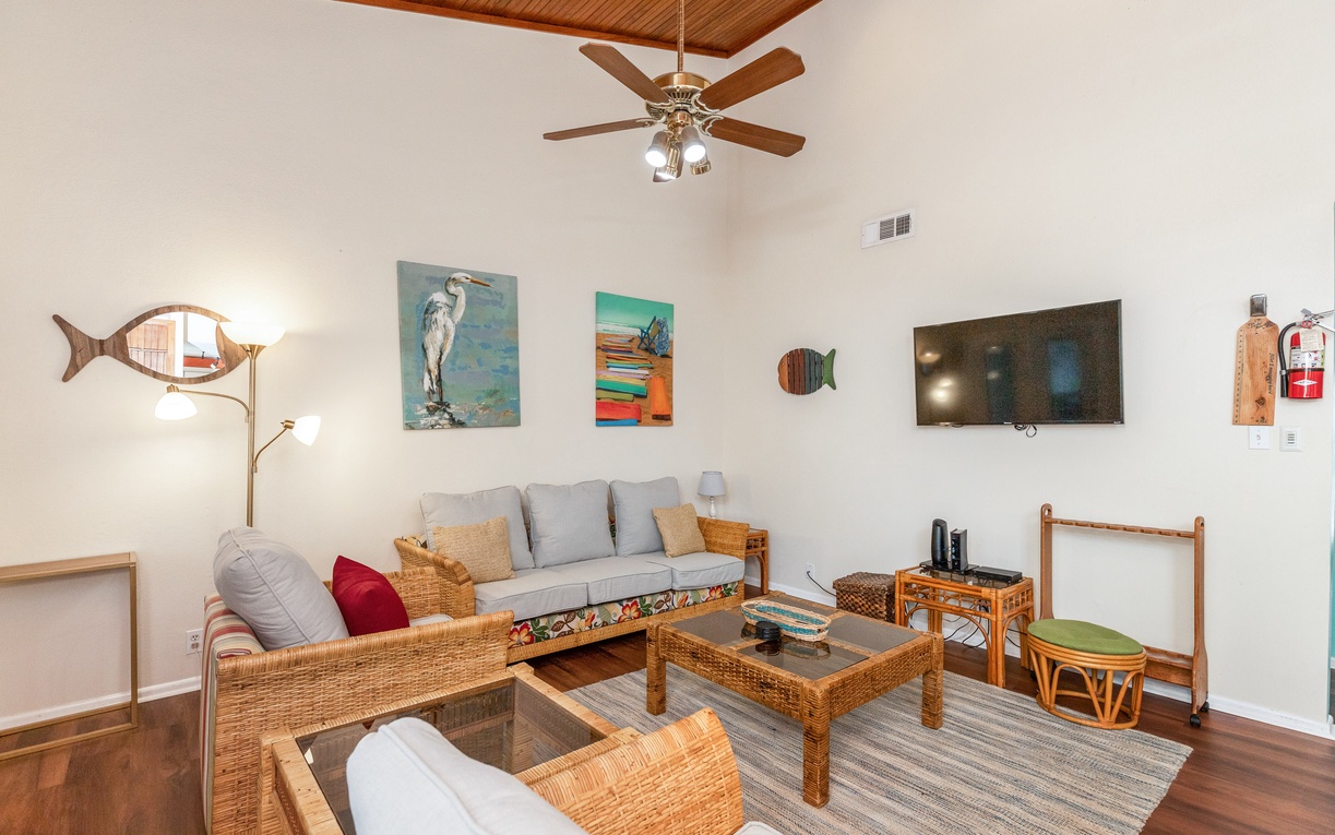 Relax in your coastal-themed living room with wicker furniture, cheerful art, and a ceiling fan keeping you cool.