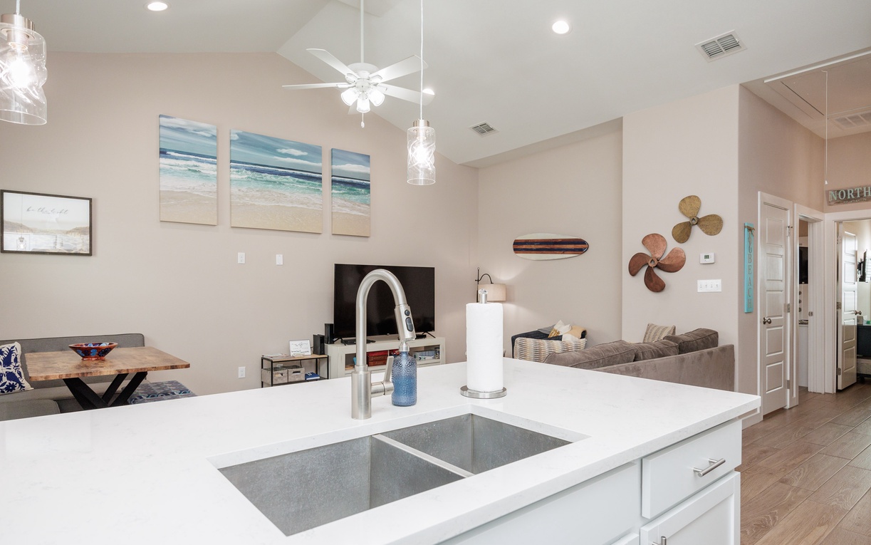 Your open-concept kitchen flows seamlessly into the living space, featuring pristine white counters and modern fixtures for effortless meal prep.