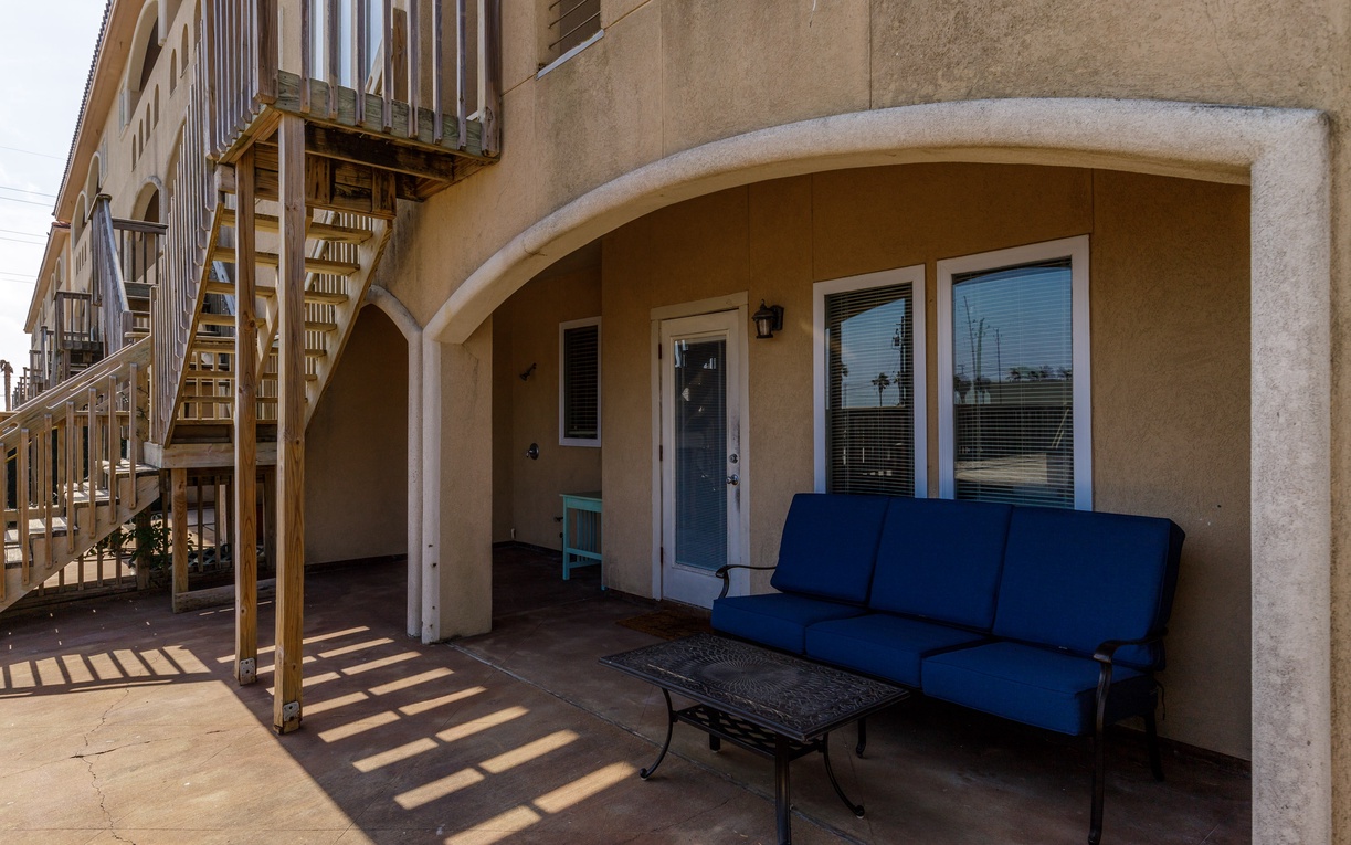 Your private covered patio offers comfortable seating with blue cushions, perfect for morning coffee or evening relaxation outdoors.