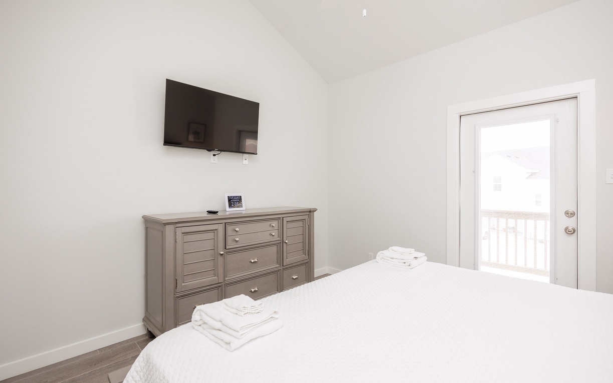 Your bright bedroom features crisp linens, a wall-mounted TV, and elegant dresser storage for a comfortable stay.