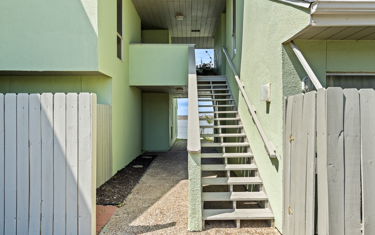 Charming green duplex with separate entrances and private outdoor spaces, surrounded by peaceful residential fencing.