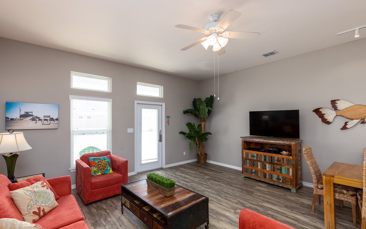 Relax in your bright, airy living room with cozy coral seating, rustic wood accents, and tropical touches that create the perfect coastal retreat.
