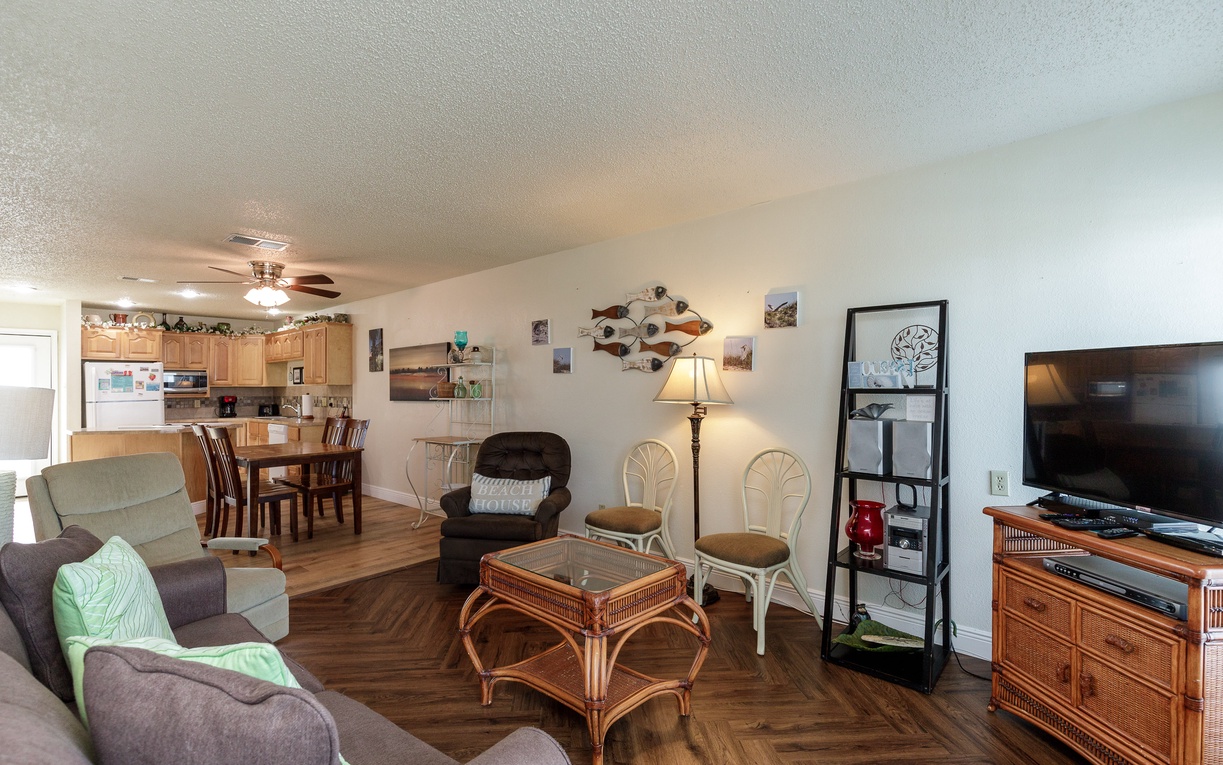 Relax in your spacious open-concept living area with coastal charm, featuring comfortable seating, dining space, and fully equipped kitchen for memorable meals.