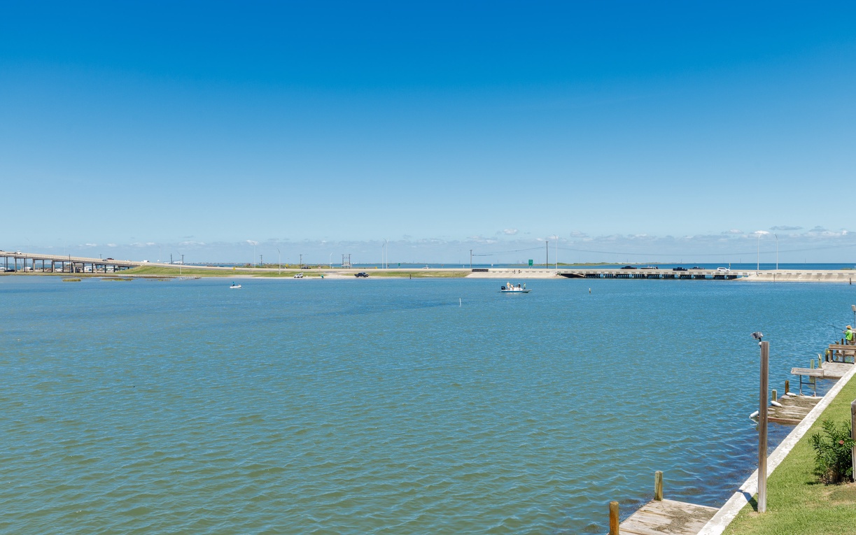 Peaceful waterfront setting with pristine bay waters, distant bridges, and serene boating atmosphere under clear blue skies.