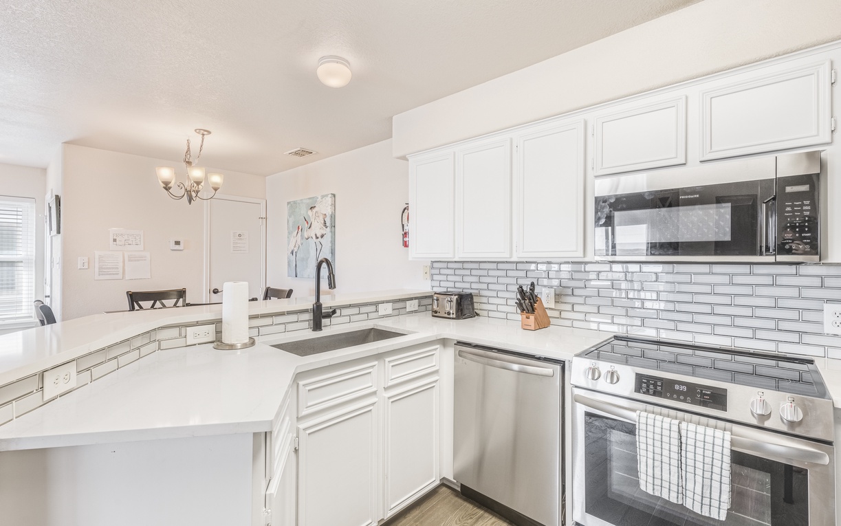 You'll love cooking in this bright, modern kitchen with pristine white cabinets, subway tile backsplash, and stainless steel appliances.