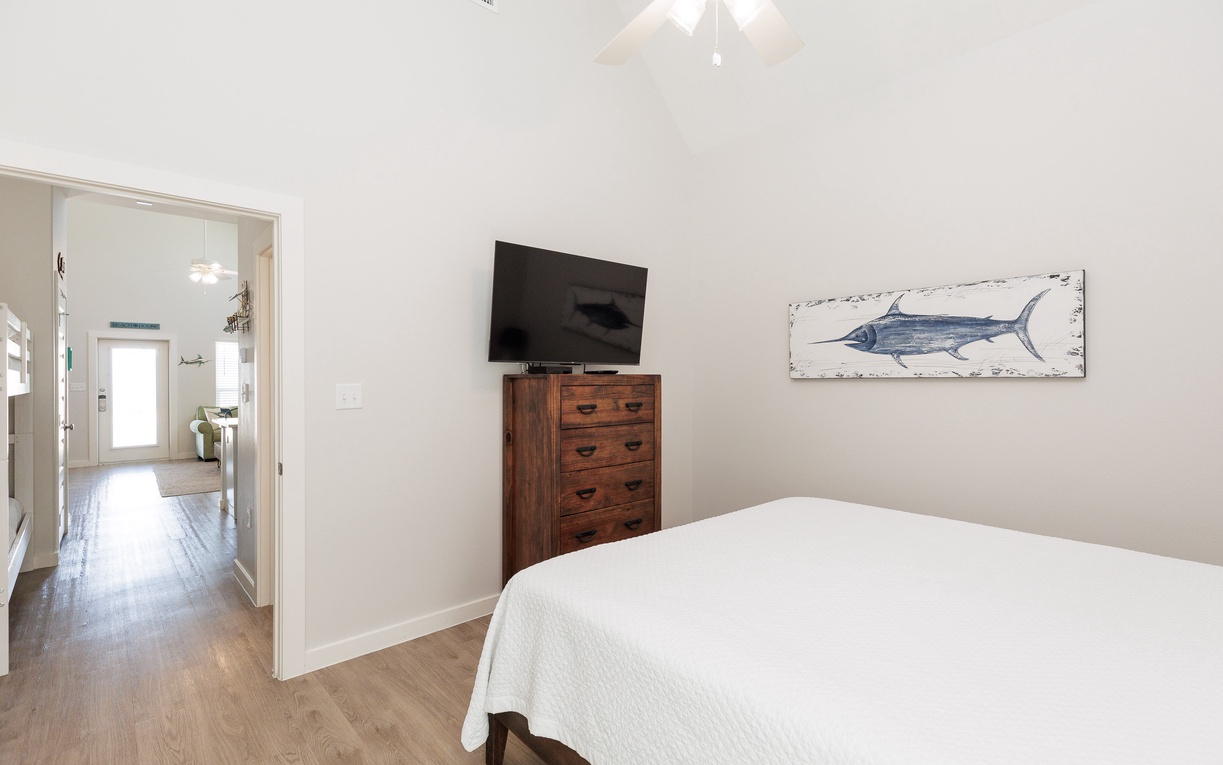 Rest peacefully in your serene bedroom with coastal charm, featuring a comfortable bed, entertainment center, and nautical artwork.
