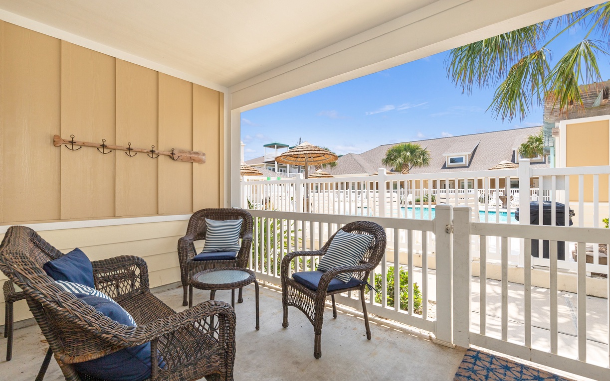 Relax on your private patio with comfortable wicker seating and stunning pool views framed by swaying palm trees.
