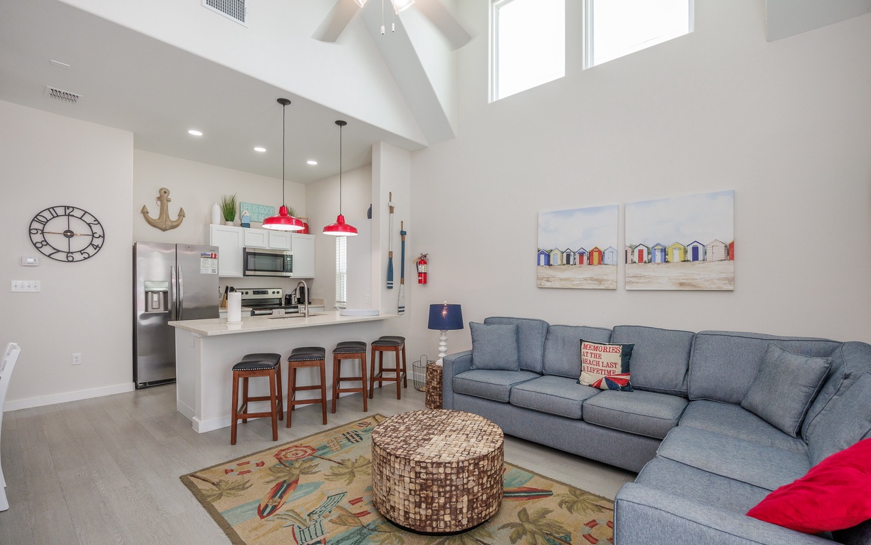 Relax in your bright open-concept living space with soaring ceilings, cozy sectional seating, and a fully equipped kitchen perfect for home-cooked meals.