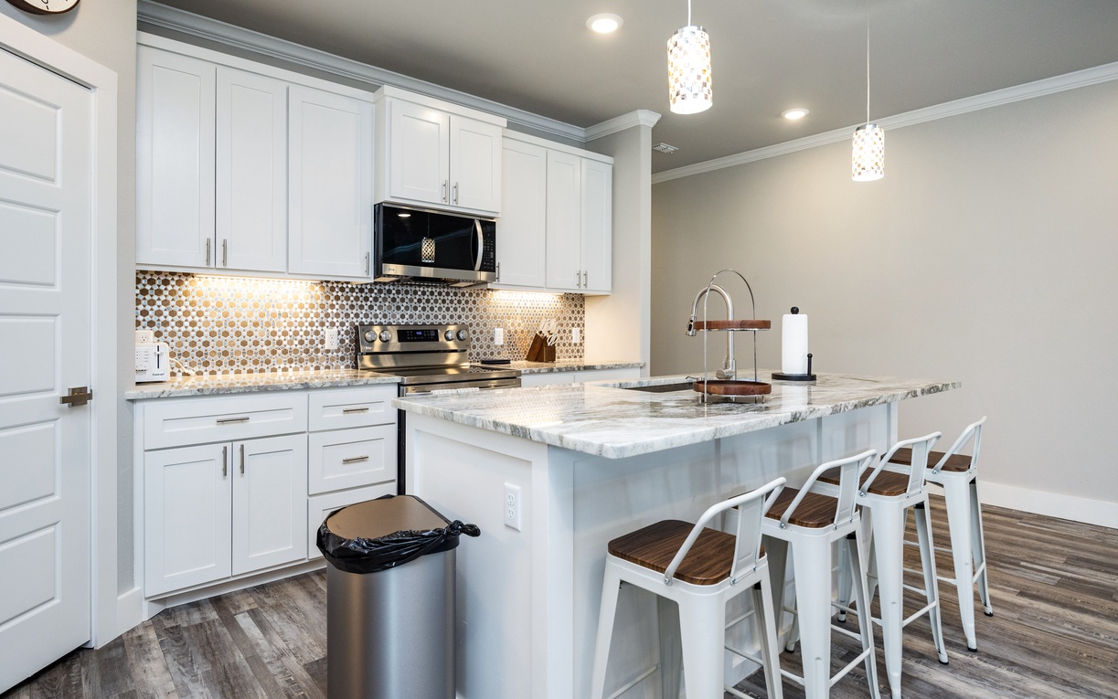 Your sleek kitchen awaits with marble counters, gleaming appliances, and a breakfast bar perfect for morning coffee or evening conversations.