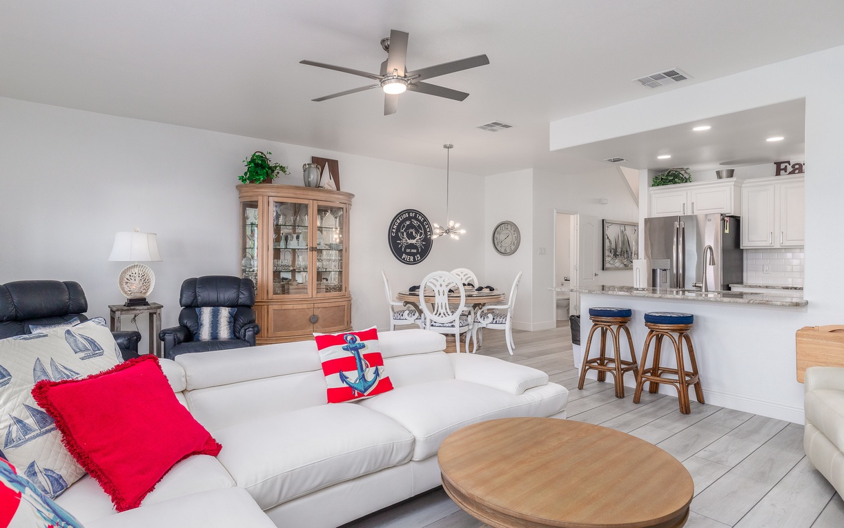 Relax in your spacious open-plan living area with comfortable seating, modern kitchen, and cheerful nautical touches throughout.