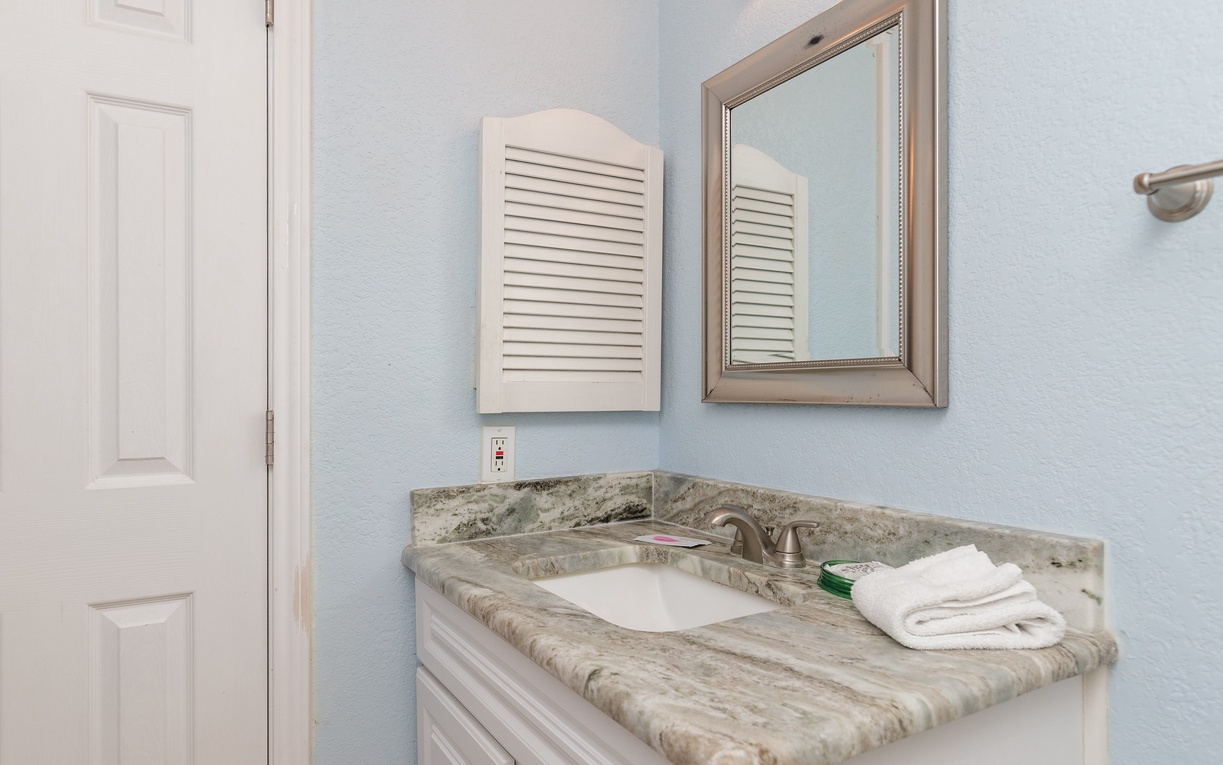 Refresh yourself at your private vanity with elegant marble countertops and soft coastal blues creating a serene morning routine.