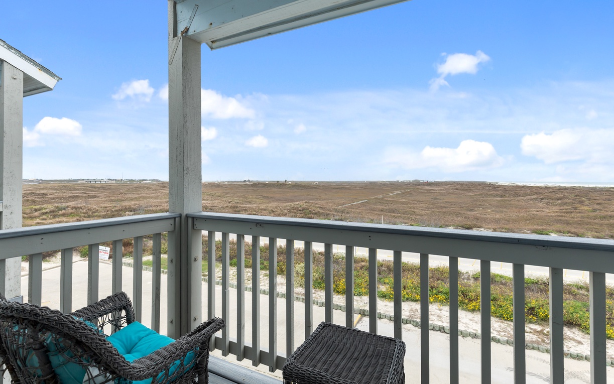 Peaceful balcony overlooking expansive coastal dunes and blue skies, perfect for morning coffee or evening relaxation.