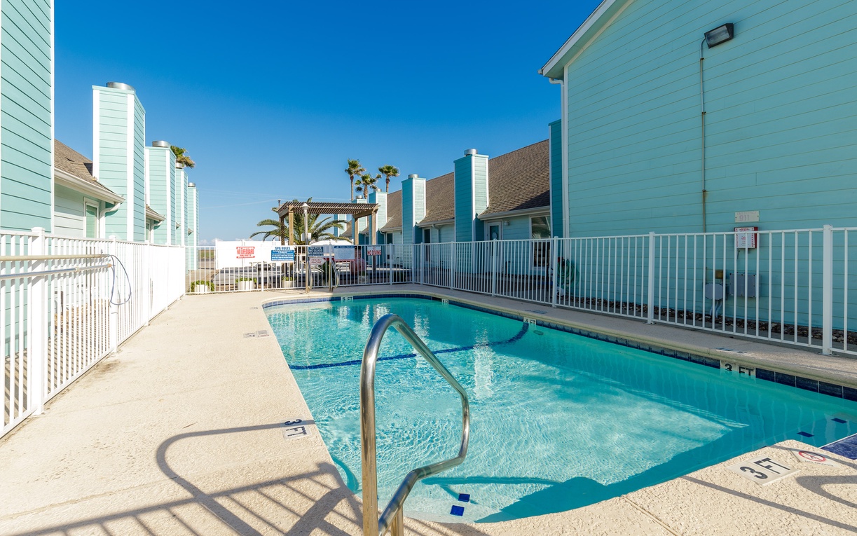 Sparkling community pool surrounded by coastal townhomes, offering your perfect spot for morning swims or afternoon relaxation under the California sun.