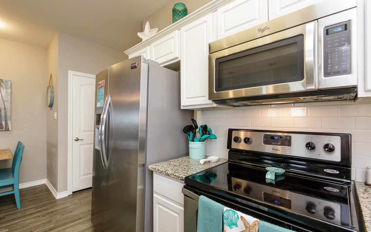 Your fully equipped kitchen awaits with granite counters, stainless appliances, and coastal charm—perfect for preparing meals during your stay.