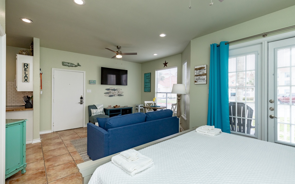 Unwind in your coastal-themed studio with vibrant touches, plush bed, and bright living space opening to your private balcony.