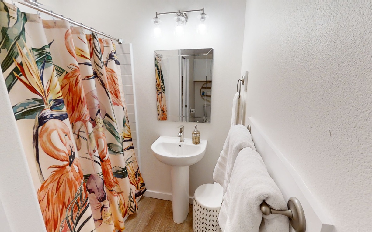 Step into your bright, tropical-inspired bathroom where vibrant floral curtains add a cheerful touch to your refreshing shower routine.