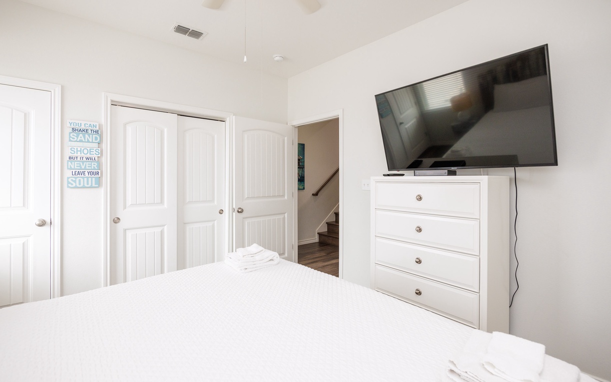 Wake up in this bright, airy bedroom featuring a large flat-screen TV and ample storage in the pristine white dresser.