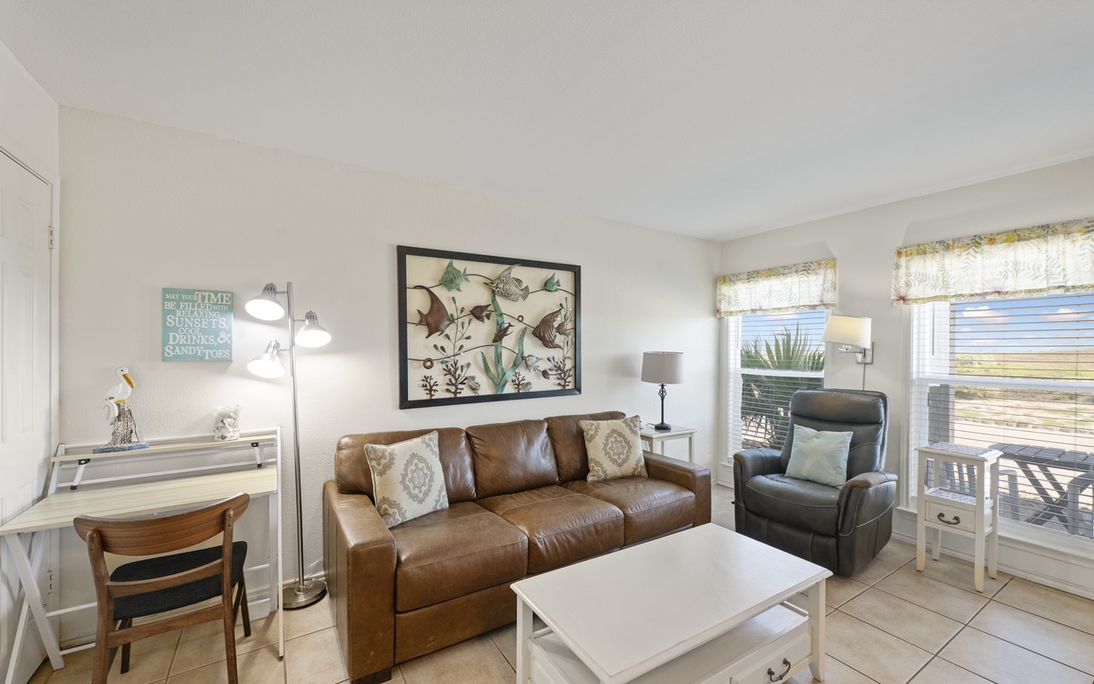 Settle into your comfortable leather sofa and enjoy the coastal-inspired living space with natural light streaming through windows.