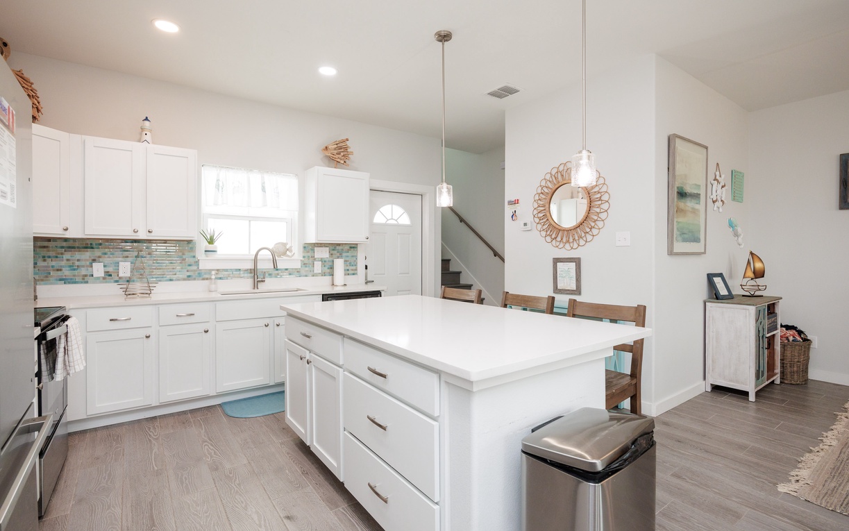 Cook together in this bright, spacious kitchen featuring sleek white cabinets, marble countertops, and a perfect island for meal prep and casual dining.