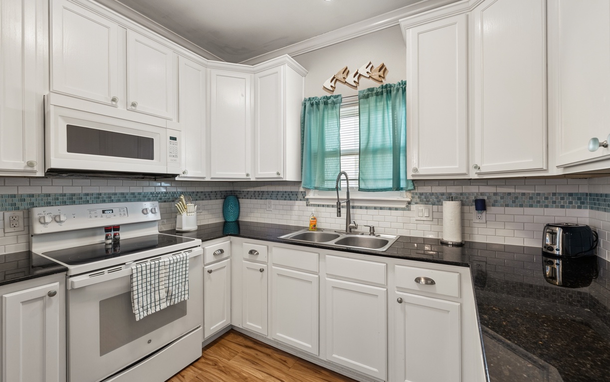 Your fully equipped kitchen features sleek granite counters and coastal-inspired tile, making meal prep feel like a vacation ritual. Brew your morning coffee here and plan your day's adventures.