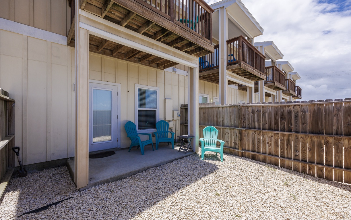 Step outside to your private patio where colorful Adirondack chairs await under the covered area—perfect for morning coffee or evening relaxation.