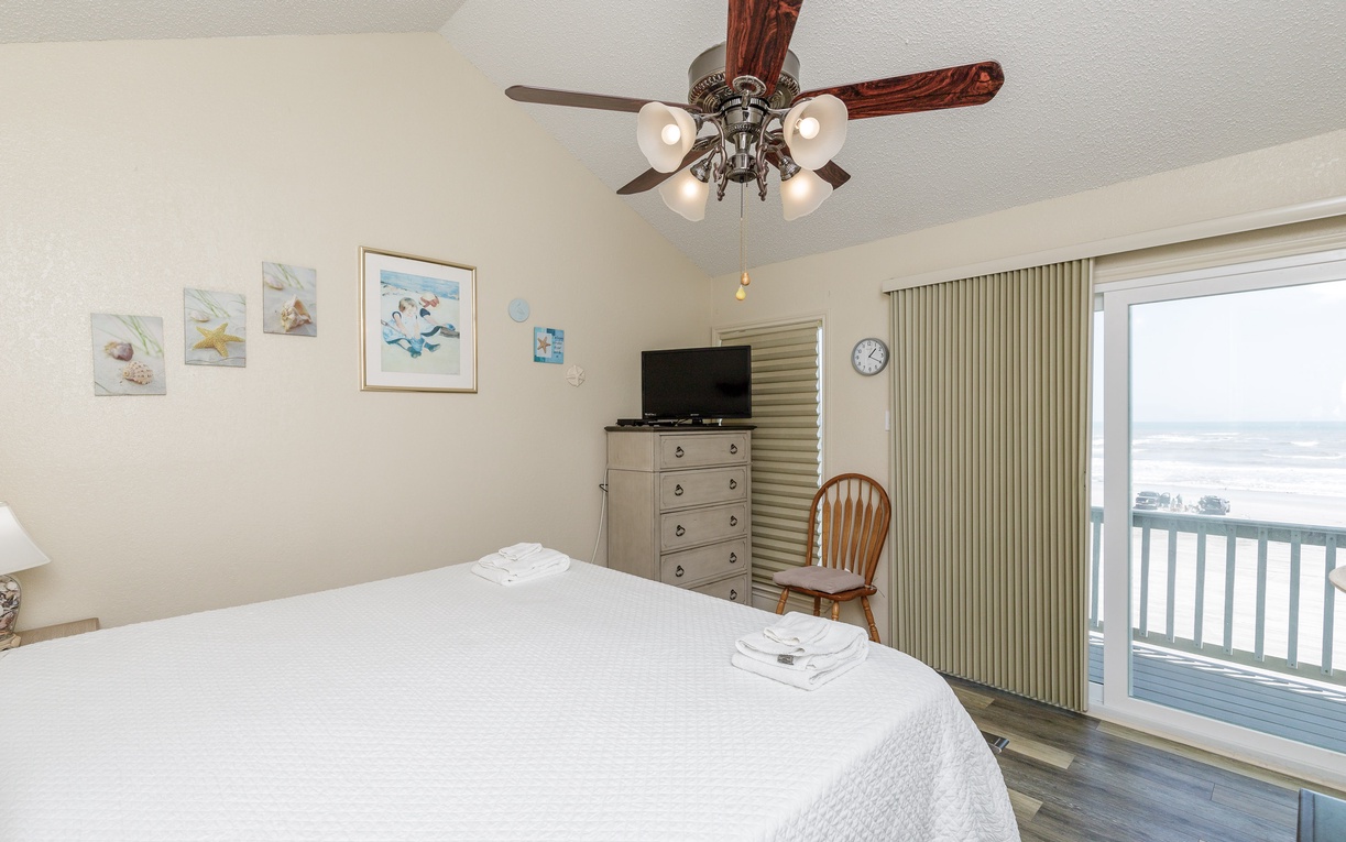 Primary bedroom with king size bed, private beachfront balcony, and ensuite bathroom