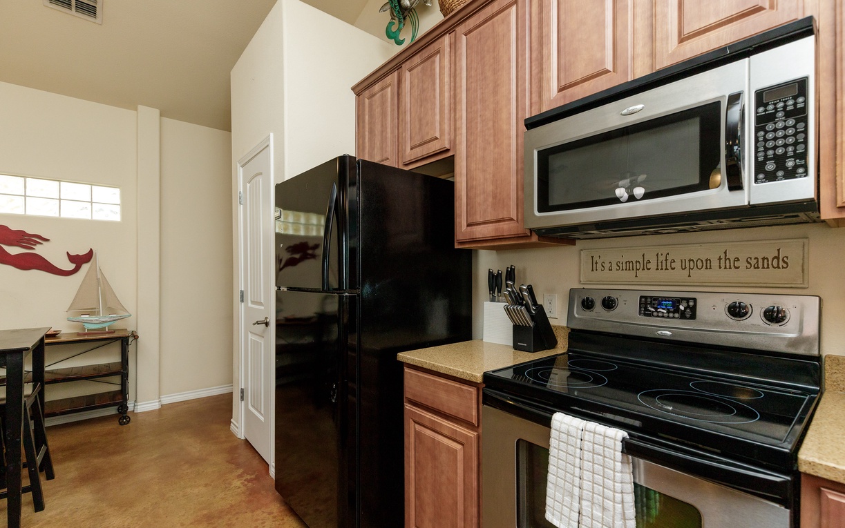 Your fully equipped kitchen awaits with warm wood cabinets, sleek appliances, and coastal charm for preparing memorable vacation meals.