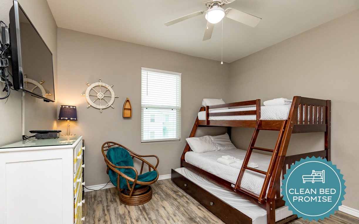 Your cozy nautical-themed bedroom features a comfortable bunk bed with trundle, ceiling fan, and charming maritime décor perfect for family stays.