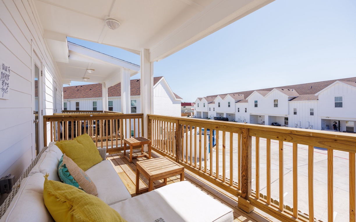 Your covered balcony invites relaxation with comfortable seating and warm wood finishes, perfect for morning coffee or evening unwind.