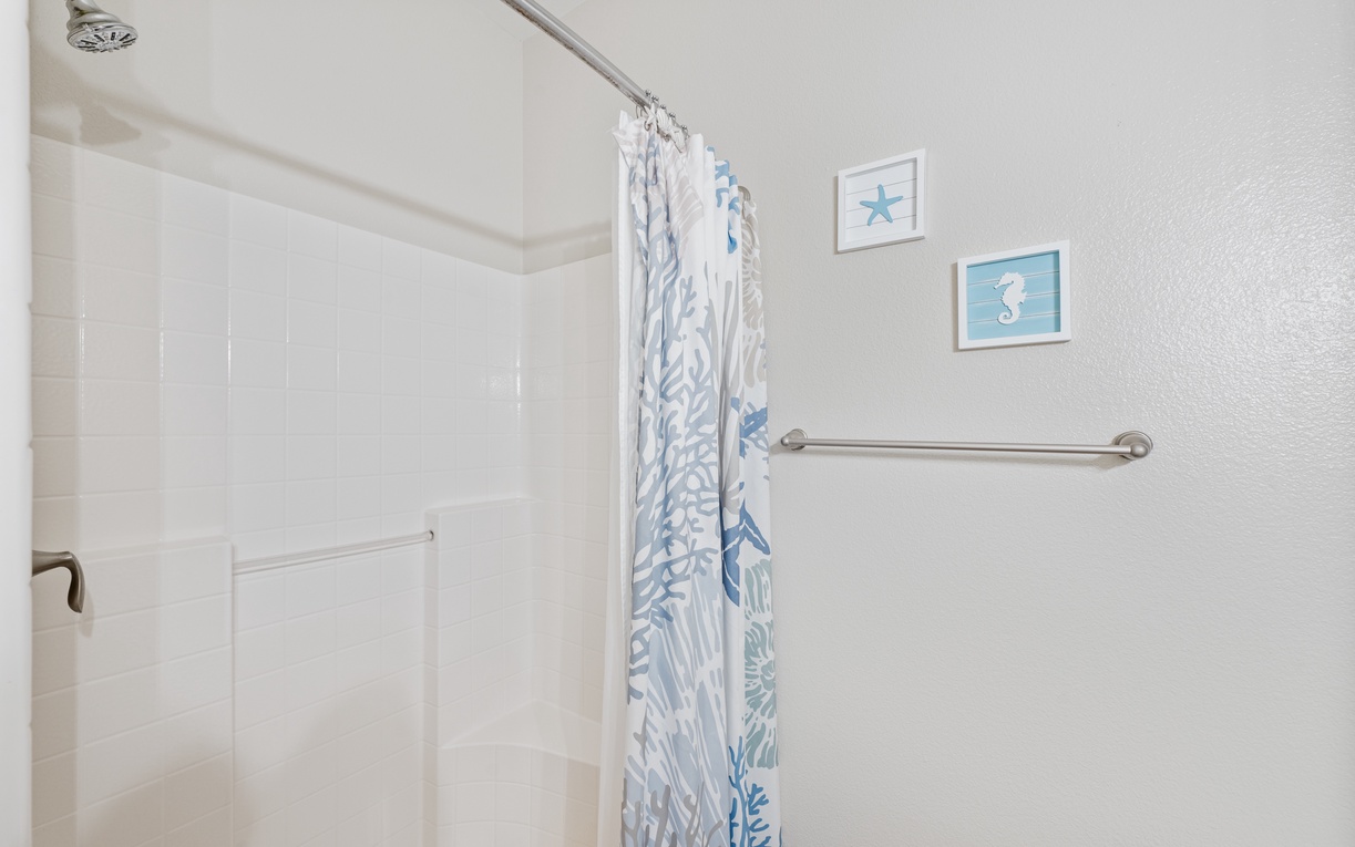 Your bright, spacious shower features coastal decor and safety rails for comfort.