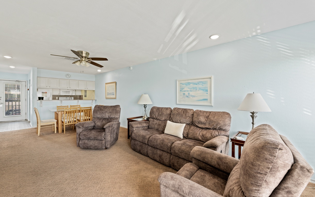 Stretch out in your spacious living area, where plush seating and coastal breezes from the ceiling fan invite you to unwind. Gather around the dining table for meals, laughter, and vacation memories.