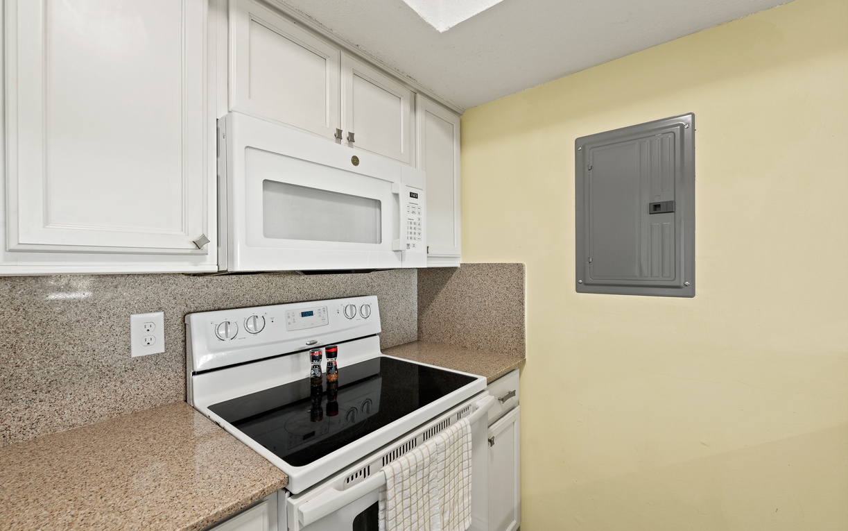 You'll love preparing your favorite meals in this well-equipped kitchen, featuring a sleek electric stove and convenient microwave to make cooking easy and enjoyable.
