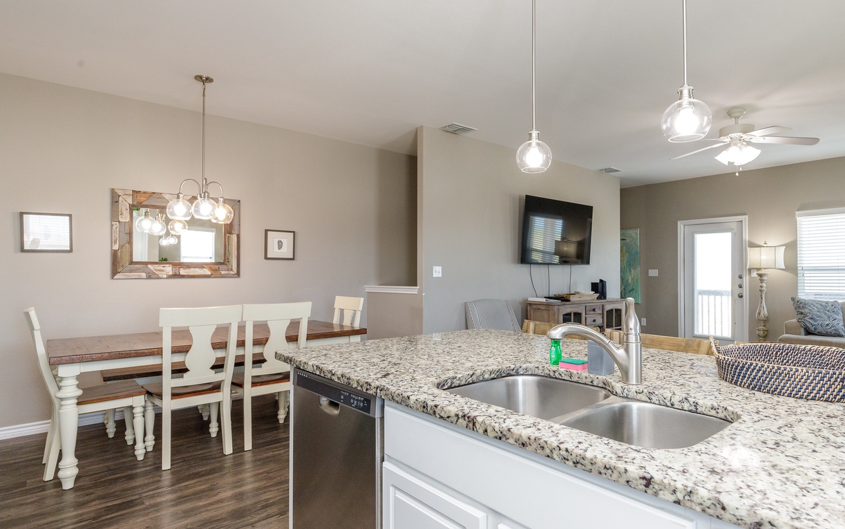 Your open-concept kitchen flows seamlessly into the dining area, where granite countertops and pendant lighting create an inviting space for cooking together.