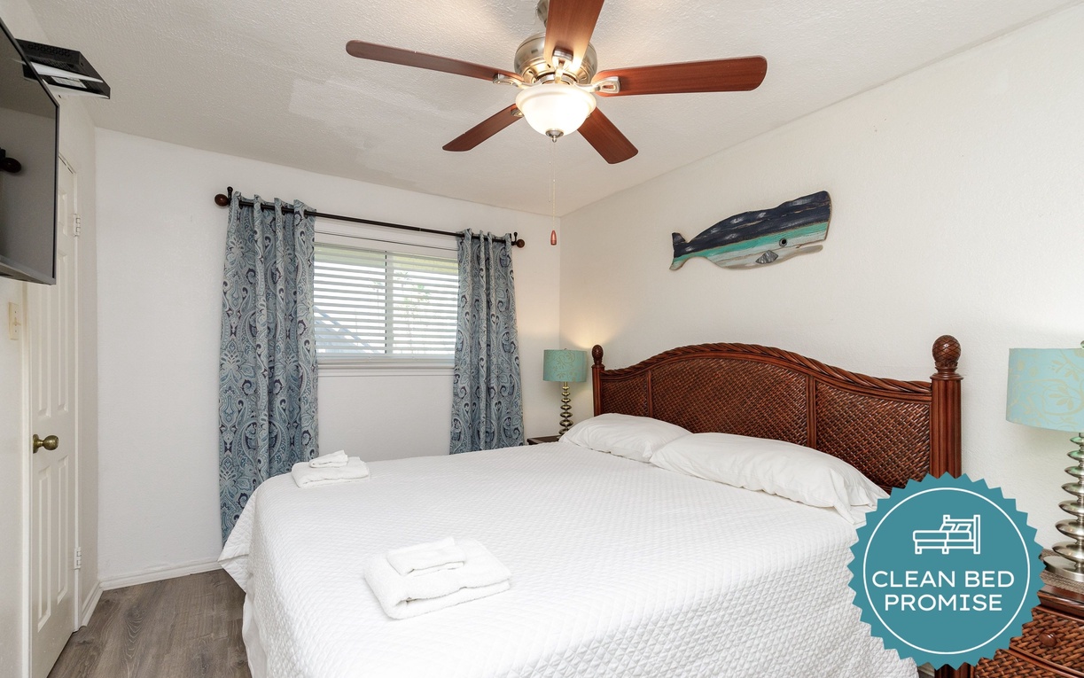 Drift off in this coastal-themed bedroom with comfortable bed, ceiling fan, and ocean artwork creating your perfect seaside retreat.