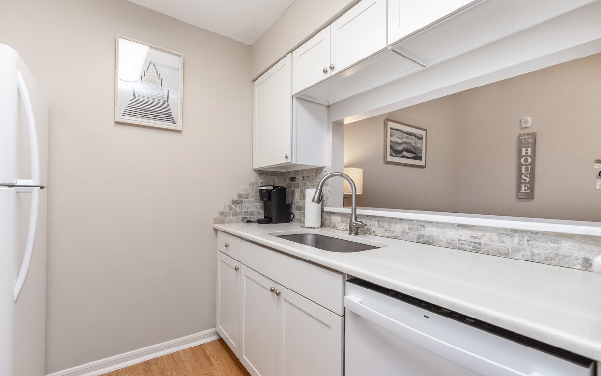 Your bright galley kitchen features gleaming white cabinets, marble countertops, and modern appliances for all your culinary adventures.