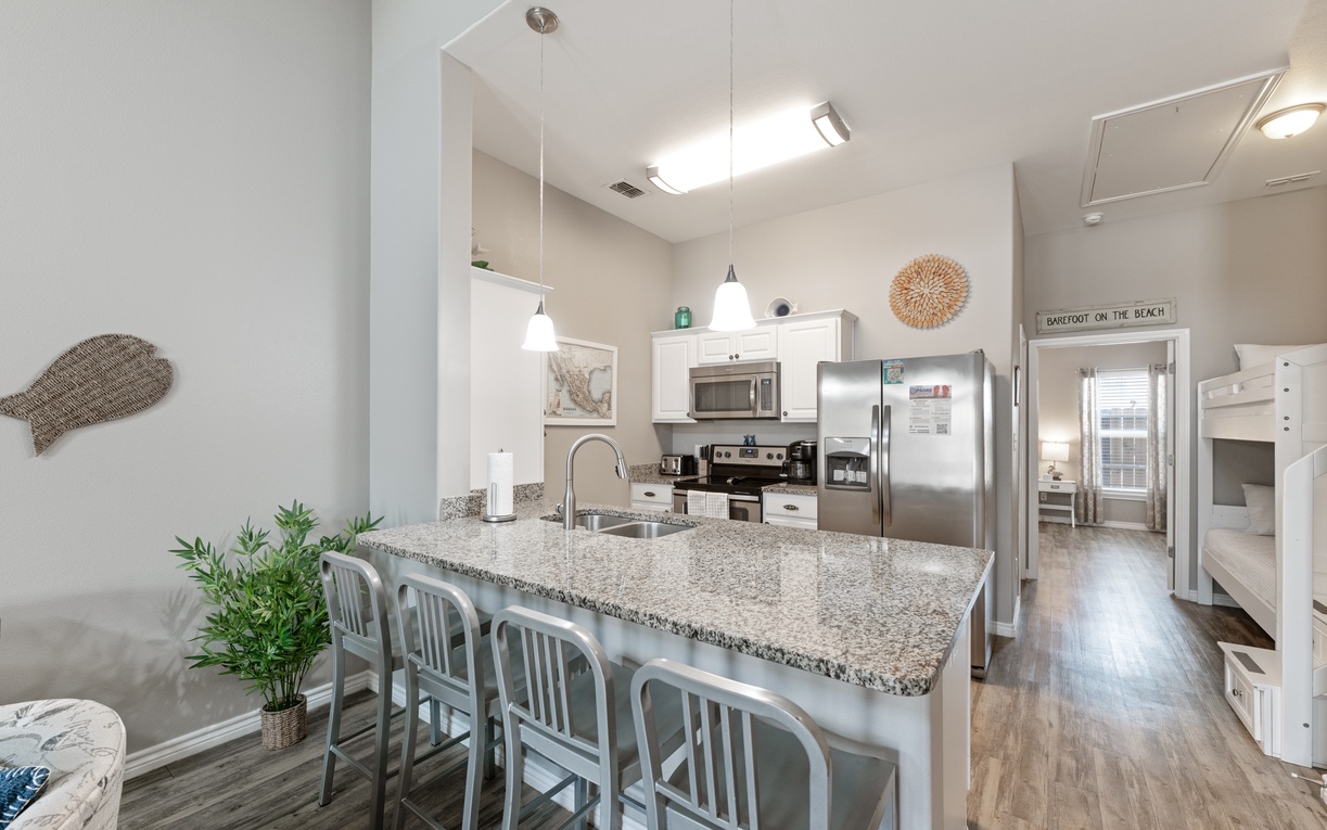 Your bright open kitchen awaits with granite counters, stainless appliances, and a breakfast bar perfect for morning coffee or evening conversations.