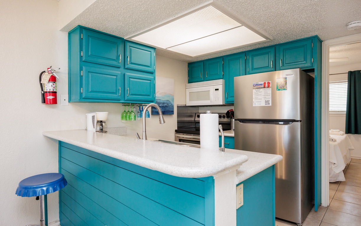 Your vibrant turquoise kitchen awaits with modern appliances, granite counters, and everything needed to create delicious vacation memories.