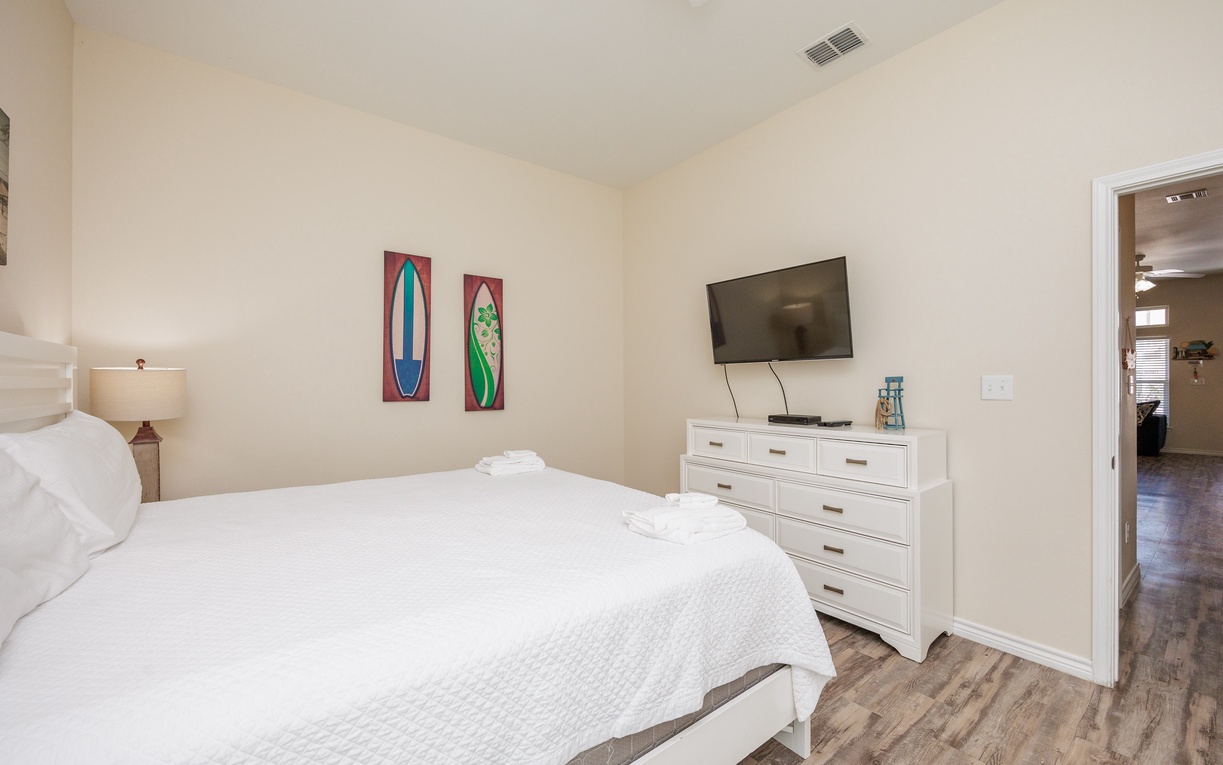 Sink into fresh white linens and drift off while surfboard art adds coastal charm to your peaceful retreat.