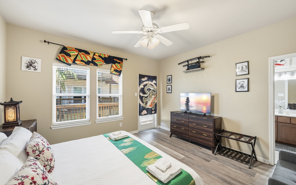Unwind in your serene bedroom with Asian-inspired décor, a plush bed, ceiling fan, and entertainment at your fingertips. Soft light and thoughtful touches make this your perfect retreat.