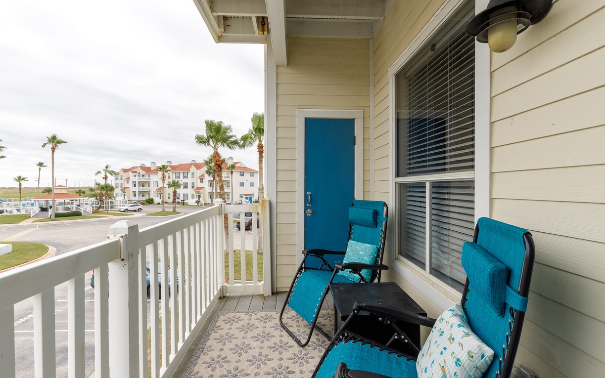 Unwind on your private balcony with comfortable lounge chairs overlooking tropical palms and coastal architecture.
