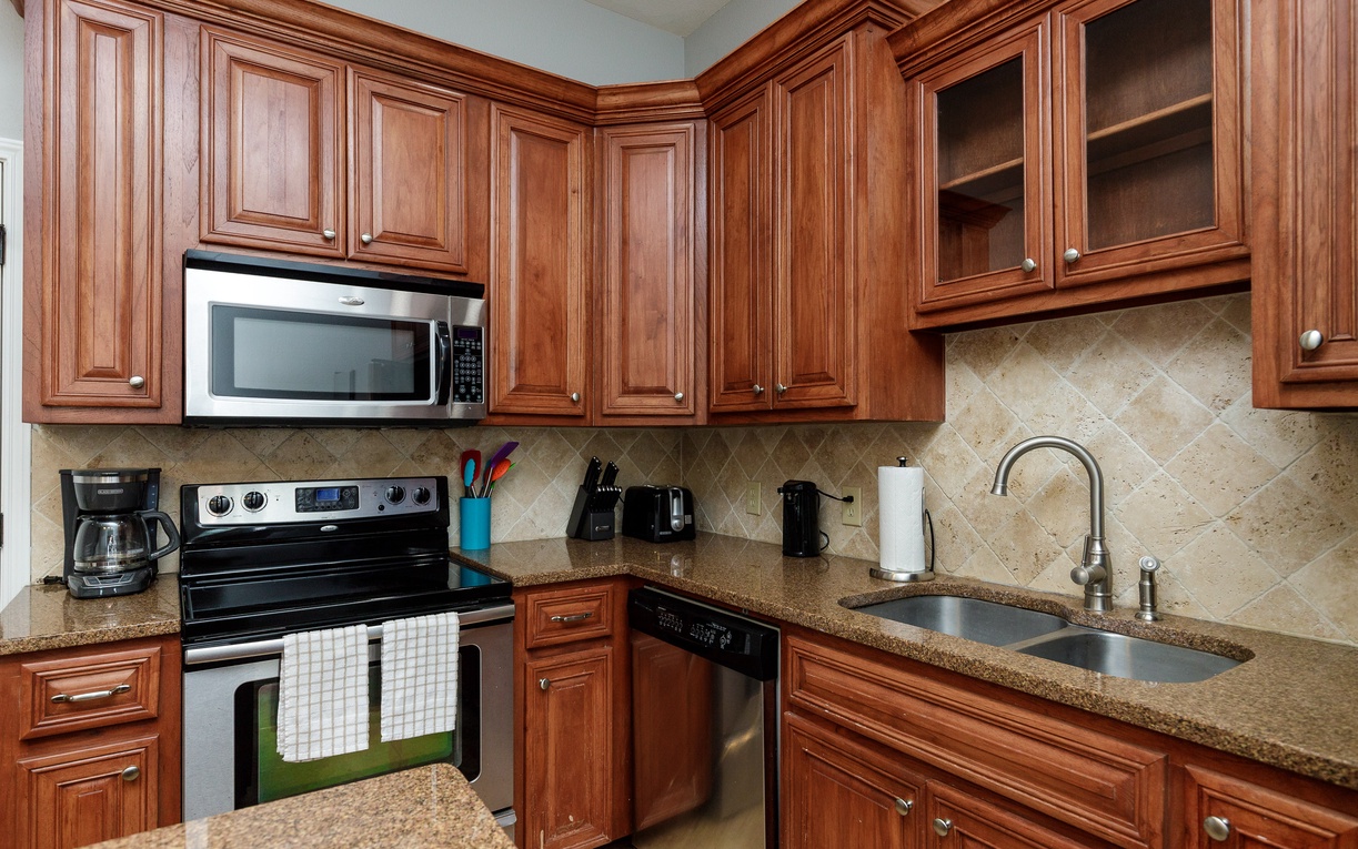 Step into your fully equipped kitchen with rich wood cabinetry, granite counters, and modern appliances for preparing memorable meals.